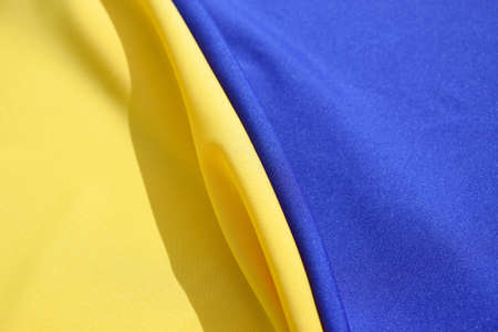 Fabric bent national flag of Ukraine, UA. Blue and yellow colors. close-up, background.の写真素材