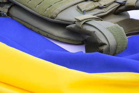 Tactical, military body armor with plates on the background of the flag of Ukraine. The concept of...
