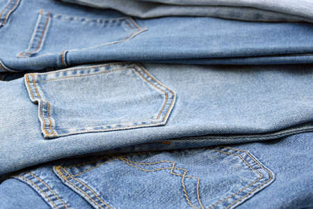 Lots of jeans pants in a stack. Denim background. The concept of buying, selling, shopping and trendy modern clothes.の写真素材