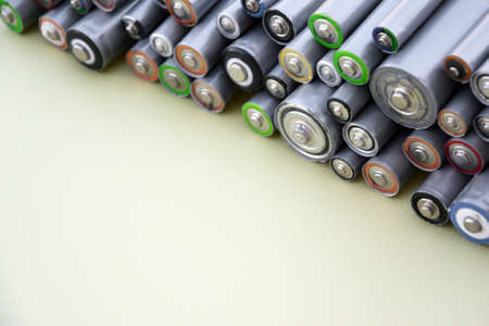 Used AA batteries and proper disposal of environmentally and soil-toxic batteries on a green...