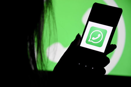 Kharkiv, Ukraine - December 20, 2021: A phone with a Whatsapp screen in the hands of a young girl against the background of a monitor. selective focus.のeditorial素材