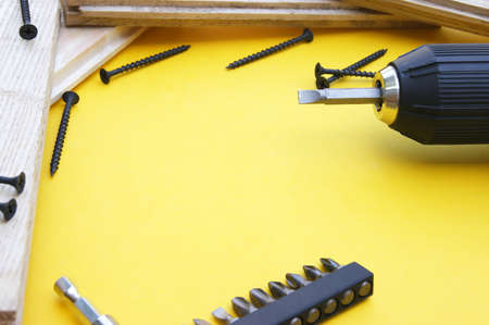 Yellow-black screwdriver on a yellow background, screws, a set of bits. Copy space.の写真素材