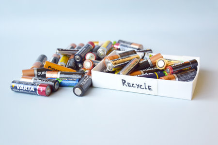 KHARKIV, UKRAINE - February 22, 2022: Used AA batteries and proper disposal of environmentally and soil toxic batteries on a blue background. The concept of processing harmful and recyclable objects.のeditorial素材
