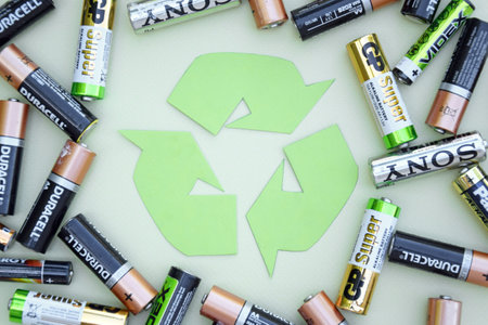KHARKIV, UKRAINE - JUNE 11, 2022: Used AA batteries and proper disposal of environmentally and soil toxic batteries on a green background. The concept of processing harmful and recyclable objects.のeditorial素材