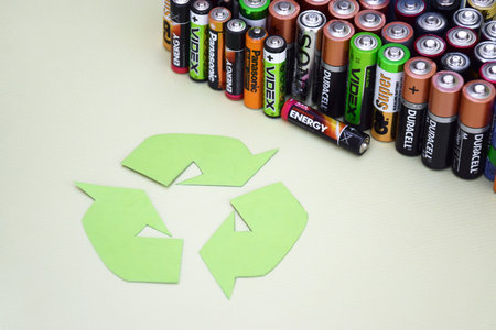 KHARKIV, UKRAINE - JUNE 11, 2022: Used AA batteries and proper disposal of environmentally and soil toxic batteries on a green background. The concept of processing harmful and recyclable objects.のeditorial素材