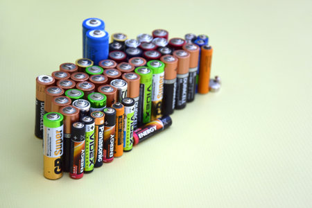 KHARKIV, UKRAINE - JUNE 11, 2022: Used AA batteries and proper disposal of environmentally and soil toxic batteries on a green background. The concept of processing harmful and recyclable objects.のeditorial素材