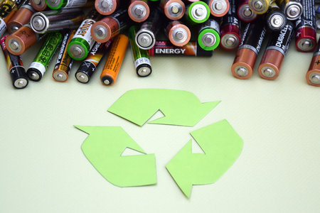 KHARKIV, UKRAINE - JUNE 11, 2022: Used AA batteries and proper disposal of environmentally and soil toxic batteries on a green background. The concept of processing harmful and recyclable objects.のeditorial素材