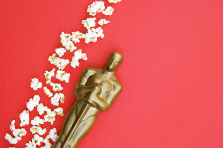 Plastic Oscar award on a red background with popcorn.のeditorial素材