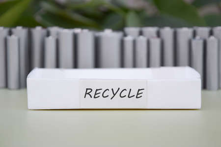 Used AA batteries and proper disposal of environmentally and soil-toxic batteries on a green background.の写真素材