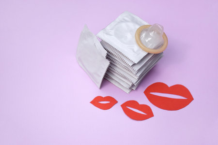 Many white packages of unopened condoms with paper kisses. Using a condom to reduce the chance of pregnancy or sexually transmitted diseases, STDs. The concept of safe sex and reproductive health.の写真素材