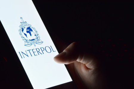Person holding smartphone with Interpol logo displayed on screen.