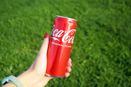 Kharkiv, Ukraine - September 18, 2022: One can of Coca-Cola soda in a woman's hand. Coca-Cola is a world famous non-alcoholic carbonated drink produced by the Coca-Cola Company.のeditorial素材