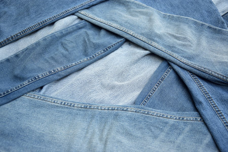 Lots of jeans pants in a stack. Denim background. The concept of buying, selling, shopping and trendy modern clothes.の写真素材