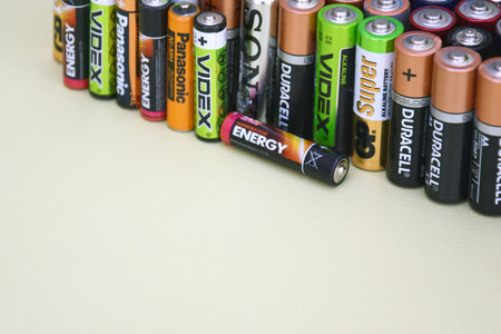 KHARKIV, UKRAINE - JUNE 11, 2022: Used AA batteries and proper disposal of environmentally and soil toxic batteries on a green background. The concept of processing harmful and recyclable objects.のeditorial素材