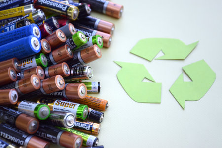 KHARKIV, UKRAINE - JUNE 11, 2022: Used AA batteries and proper disposal of environmentally and soil toxic batteries on a green background. The concept of processing harmful and recyclable objects.のeditorial素材