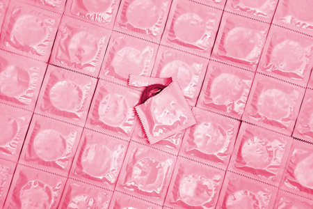 Many white packages of unopened condoms as a background. Image toned in Viva Magenta, color of the 2023 year.の写真素材