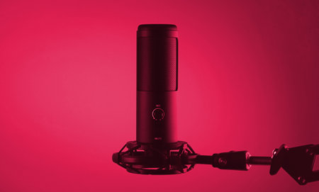 Studio condenser microphone isolated on dark background. Image toned in Viva Magenta, color of the 2023 year.の写真素材