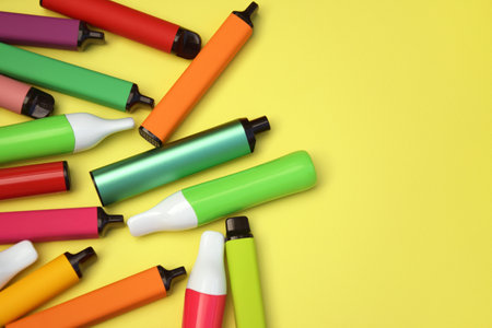 Set of multicolor disposable electronic cigarettes on a bright yellow background. The concept of modern smoking, vaping and nicotine.の写真素材