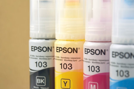 KHARKIV, UKRAINE - FEBRUARY 11, 2023: Four bottles of ink Epson, yellow, red, blue, black, built-in to the Epson L3150 series printer.のeditorial素材
