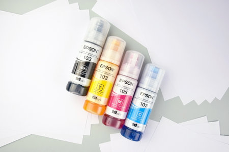KHARKIV, UKRAINE - FEBRUARY 11, 2023: Four bottles of ink Epson, yellow, red, blue, black, built-in to the Epson L3150 series printer.のeditorial素材