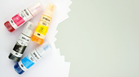 KHARKIV, UKRAINE - FEBRUARY 11, 2023: Four bottles of ink Epson, yellow, red, blue, black, built-in to the Epson L3150 series printer.のeditorial素材