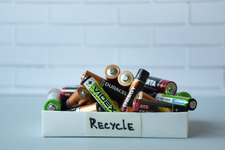 Used AA batteries and proper disposal of environmentally and soil toxic batteries on a blue background.のeditorial素材