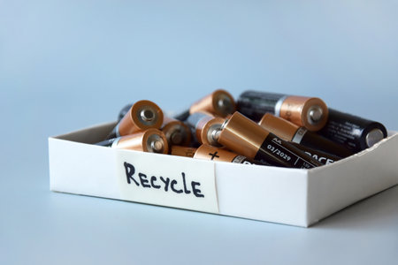 Used AA batteries and proper disposal of environmentally and soil toxic batteries on a blue background.のeditorial素材