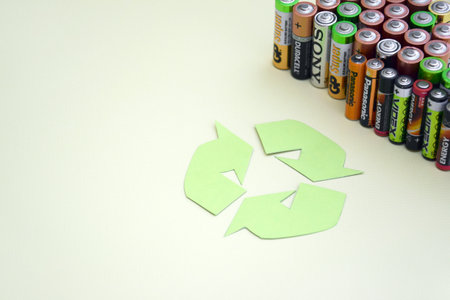 Used AA batteries and proper disposal of environmentally and soil toxic batteries on a green background.のeditorial素材