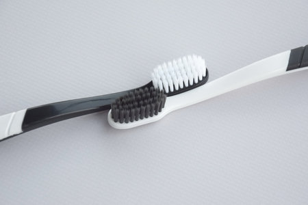 Toothbrushes with a small figure of a tooth on a light background. dental health concept.の写真素材