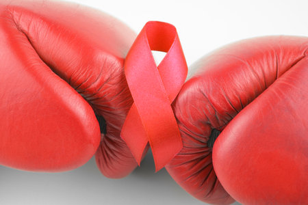 Red ribbon with boxing gloves, wrestling symbol. World AIDS Day and National HIV, AIDS and Aging Awareness Month.の写真素材