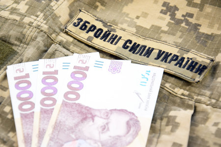 Ukrainian hryvnia against the background of a military pixel with the inscription of the armed...