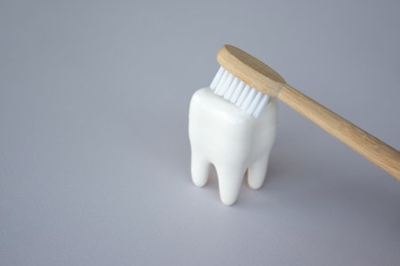 Toothbrushes with a small figure of a tooth on a light background. dental health concept.