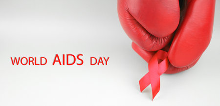 Red ribbon with boxing gloves, wrestling symbol. World AIDS Day and National HIV, AIDS and Aging Awareness Month.の写真素材