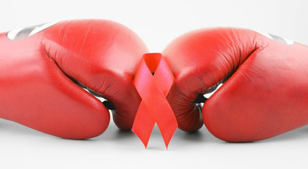 Red ribbon with boxing gloves, wrestling symbol. World AIDS Day and National HIV, AIDS and Aging Awareness Month.の写真素材