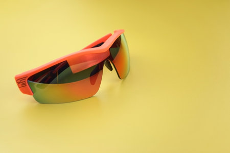 Sports goggles made of orange plastic with yellow lenses, shot against a yellow background.の写真素材