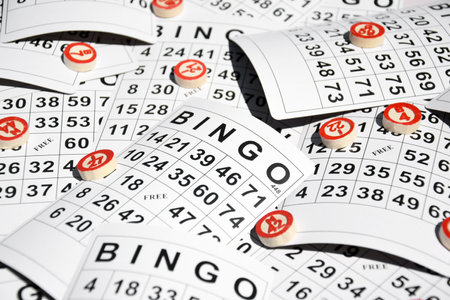 Many wooden chips with numbers and cards for a board game of bingo or lotto on a light background.の写真素材