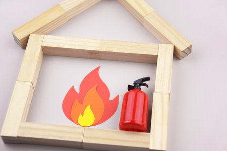 A box of matches placed next to a toy red fire extinguisher against a light background.