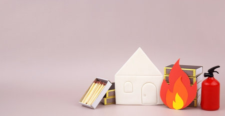 A box of matches placed next to a toy red fire extinguisher against a light background.の写真素材