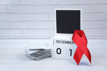 Red ribbon with calendar, symbol of struggle. December 1 is World AIDS Day and National HIV, AIDS and Aging Awareness Month.の写真素材