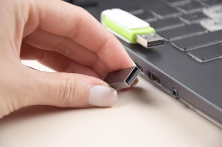 White-green USB memory stick or flash drive on the keyboard of an open laptop.