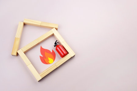 A box of matches placed next to a toy red fire extinguisher against a light background. Fire safety concept. International Firefighter's Day.の写真素材