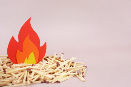 A box of matches placed next to a toy red fire extinguisher against a light background. Fire safety concept. International Firefighter's Day.の写真素材