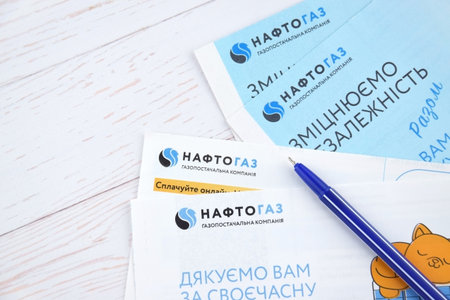 Receipt for utility services of Naftogaz with money in Ukrainian hryvnias on the light table.