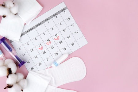 Womens menstrual pads, tampons, female menstruation calendar and alarm clock on a pink background.の写真素材