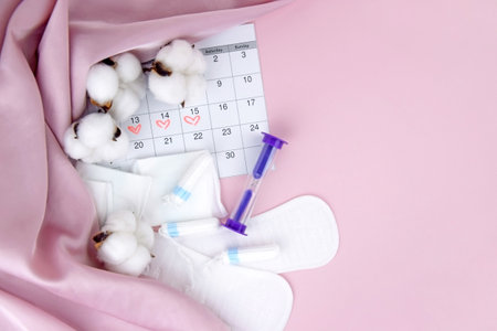 Womens menstrual pads, tampons, female menstruation calendar and alarm clock on a pink background.の写真素材