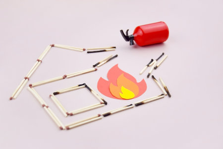 A box of matches placed next to a toy red fire extinguisher against a light background.の写真素材