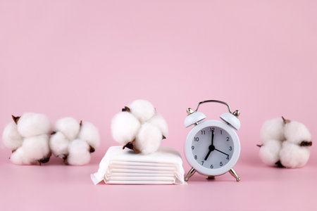 Menstrual pads, tampons, female menstruation calendar and alarm clock on a pink background.の写真素材