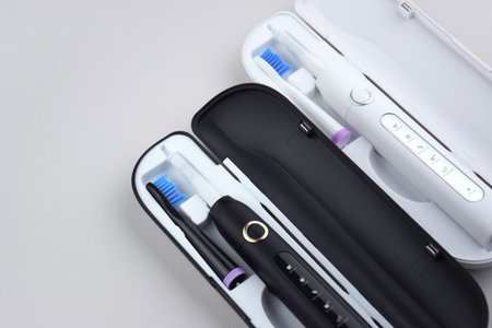 Modern electric ultrasonic toothbrush with rechargeable battery on a gray surface. Teeth care.