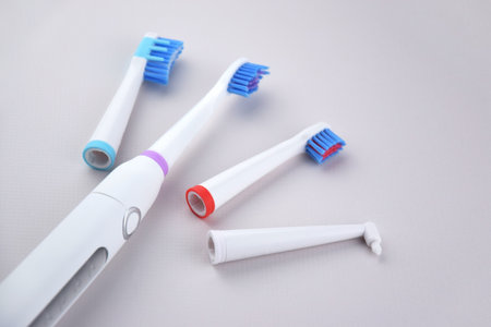 Modern electric ultrasonic toothbrush with rechargeable battery on a gray surface. Teeth care.