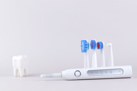 Modern electric ultrasonic toothbrush with rechargeable battery on a gray surface. Teeth care.の写真素材